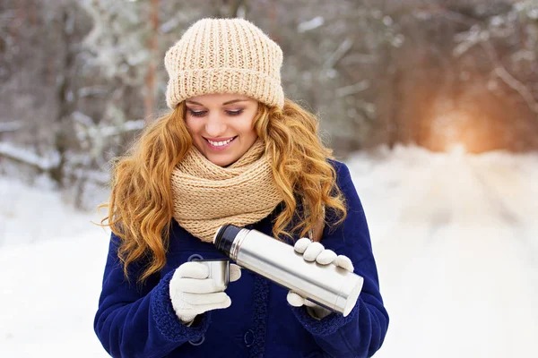 Bella giovane ragazza sorridente in giacca blu versando il tè dal termocoppa. Ragazza di viaggio . — Foto Stock