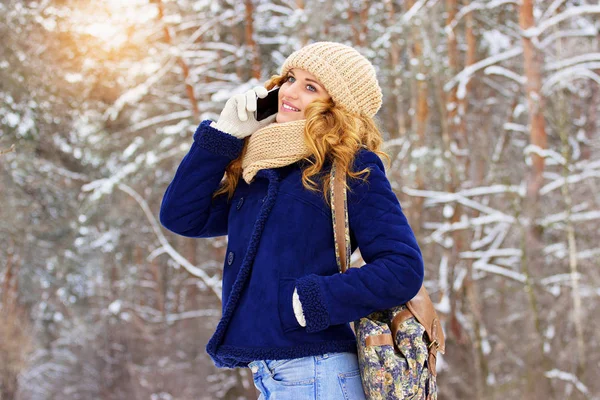 Bella giovane ragazza sorridente in giacca blu e con borsa sulla schiena a parlare al telefono. Ragazza di viaggio . — Foto Stock