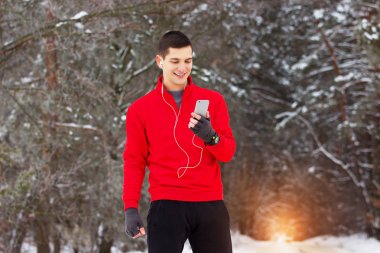 Kırmızı kazaklı onun telefon ve li kullanarak gülümseyen yakışıklı sporcu