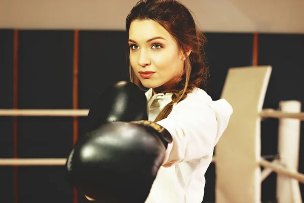 Beautiful boxing girl performs strong punch in the ring. Training at the gym. Sporty female doing boxing exercise. — Stock Photo, Image