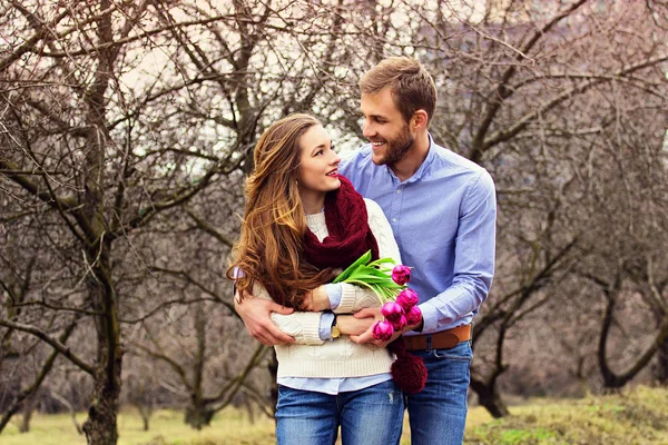 Happy grupp. Porträtt av skäggig man står bakom hans flickvän och kramar henne. Vackra leende unga par på trädgården. — Stockfoto