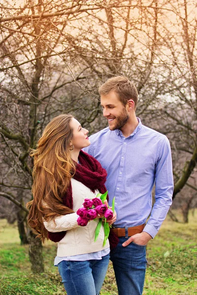 Boldogság közel áll Önhöz. Szakállas csípő ember átölelve a barátnője, a virágok, és keresi egymást. Gyönyörű fiatal pár. — Stock Fotó