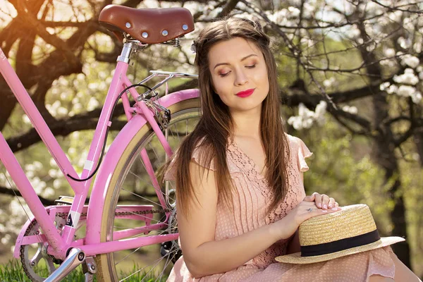 Oferty beauty. Portret młody i piękny długowłosy dziewczyna w różowej sukience siedzi w pobliżu rower różowy. — Zdjęcie stockowe