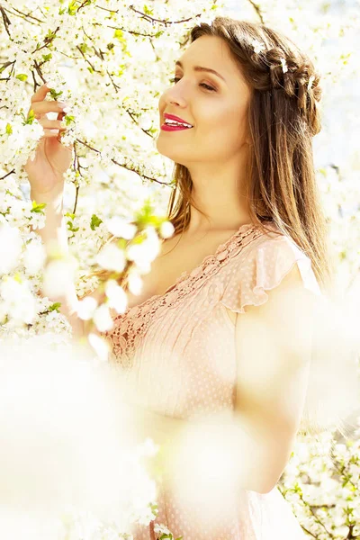 Närbild blomma porträtt av anbud, leende ung och vacker långhårig flicka i rosa klänning står på blomma bakgrund. — Stockfoto