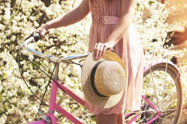 Güzellik kavramı. Pembe elbise ayakta çiçek arka plan üzerinde retro bisikleti ile genç ve güzel kız portresi. Vintage Bisiklet kavramı.