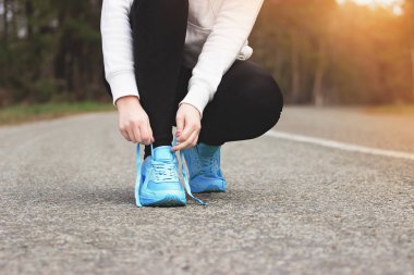 Sporcu kız çalıştırıyor. Genç portresi spor ayakkabı bağcığı bağlama yolda kız. Sağlıklı yaşam ve spor kavramları.