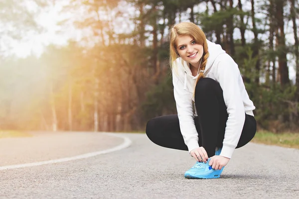 Mají brzdy. Krásná a mladá redhaired sportovní dívka vázání tkaničky na silnici parku. Fitness dopoledne. — Stock fotografie