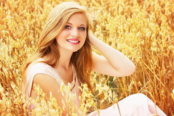 Щасливий з природою. Портрет усміхненої привабливої і красивої молодої дівчини, одягненої в біле плаття, насолоджується своїм часом, сидячи в жовтому пшеничному полі . — стокове фото