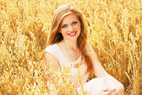 Natuurlijke schoonheid. Portret van prachtige red haired lachende meisje gekleed in witte jurk genieten van haar tijd terwijl poseren in gele tarweveld. — Stockfoto