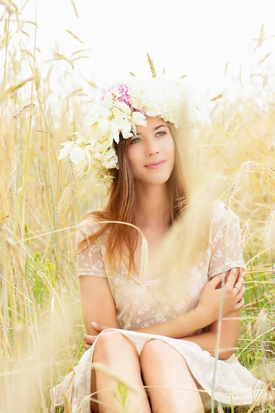 세부 사항에 있는 아름다움. 아름 다운 젊은 여자의 초상화 흰 드레스를 입은 고 그녀의 머리에 꽃은 노란 밀밭에 앉아. — 스톡 사진
