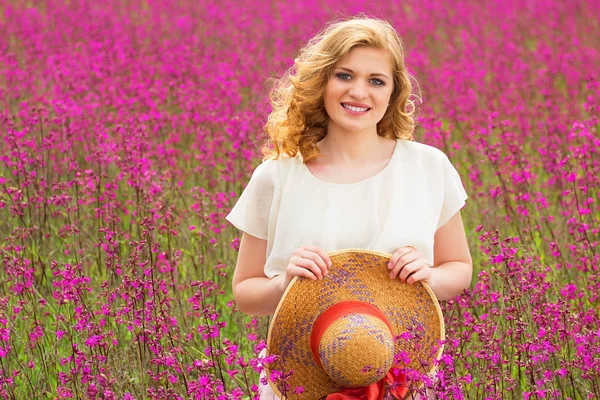 Landsbygden skönhet. Porträtt av unga och attraktiva rödhårig flicka klädd i vit klänning poserar till kameran när du står i blomma äng. — Stockfoto