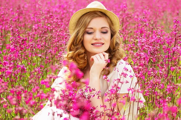 사려깊은 여자. 하얀 드레스 입은 매력적인 아름 다운 여자의 초상화와 모자는 꽃 초원에 앉아있는 동안 그에 대 한 생각. — 스톡 사진