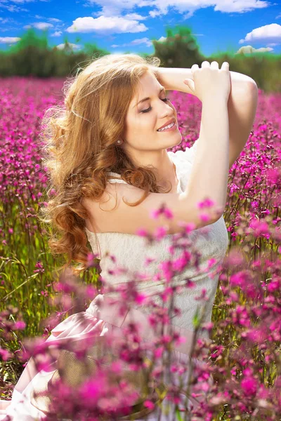 Njut av varje ögonblick. Porträtt av vackra unga rödhårig flicka i vit klänning poserar i blomma landsbygden äng. Skönhet-konceptet. — Stockfoto