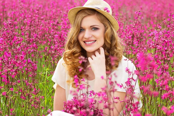 내부의 아름다움입니다. 하얀 드레스 입은 밝은 매력적인 젊은 여자의 초상화 및 모자 꽃 시골 풀밭에서 포즈. — 스톡 사진