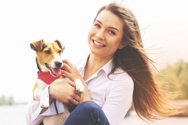 Ben ve benim güzel evde beslenen hayvan. Yakın çekim portre rahat kıyafetler kamera ellerini tutarak köpek süre için gülümseyen içinde neşeli güzel ve genç kadın.