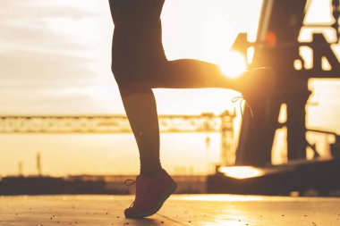 Sağlıklı bir yaşam için yürüyüş. Gün batımı ve endüstriyel görünümü arka plan üzerinde sırasında köprüde koşu çekici sportif kadın silüeti portre.