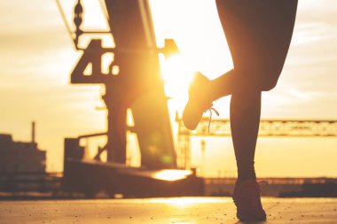 Akşam koşu. Gün batımı ve kentsel görünümü arka plan üzerinde akşam sırasında köprüde koşu genç sportif kadın silüeti portre.