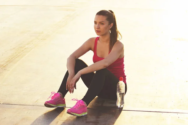 Entspannung nach dem Joggen. horizontale Aufnahme der schönen jungen Frau in Sportkleidung wirkt konzentriert und schaut weg, während sie sich nach dem Laufen ausruht. — Stockfoto