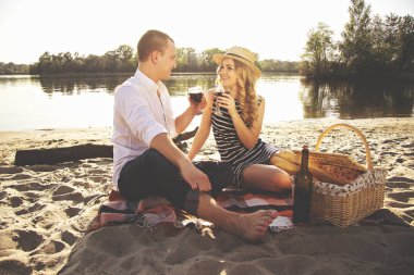 Seni çok seviyorum. Güzel genç çiftin kadehlerin şarap ile ellerinde tutmak ve birbirine romantik piknik sırasında sahilde otururken seyir yatay atış.