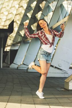 Genç ve kaygısız. Casual giyim müzik dinleme ve açık havada hareket ederken gülümseyen güzel genç kadının tam uzunlukta.