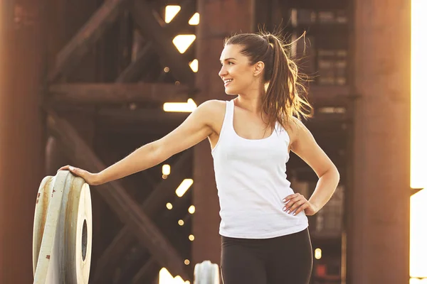 Nach gutem Training eine Bremse haben. Porträt einer attraktiven jungen Frau in Sportkleidung, die wegschaut und auf der Brücke lächelt. — Stockfoto