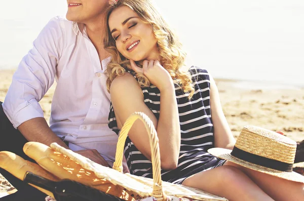 Ευτυχισμένη αγάπη ζευγάρι. Περικομμένη εικόνα όμορφη νεαρή γυναίκα, κρατώντας τα μάτια κλειστά και χαμογελώντας, ενώ κάθονται με το φίλο της στην παραλία. — Φωτογραφία Αρχείου