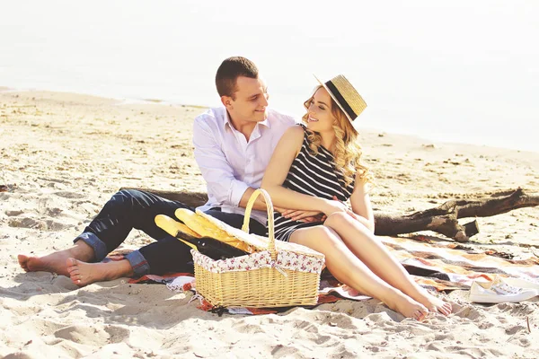 Totalement amoureuse de toi. Plan horizontal de jeune homme en tenue décontractée et belle femme se regardant et souriant tout en pique-niquant sur la plage . — Photo