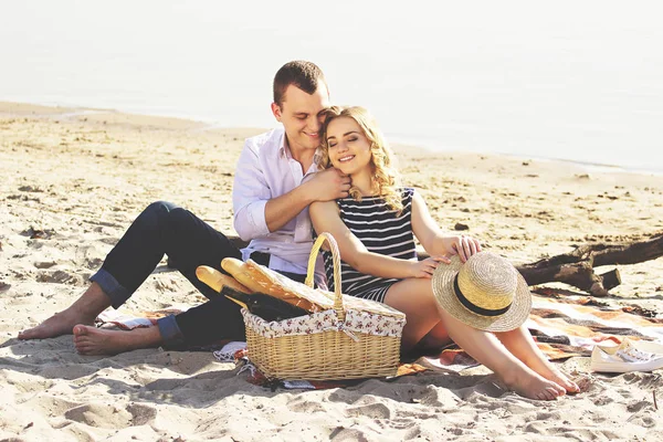 Seni çok seviyorum. Giyim gülümseyen kız arkadaşı sarılma ve sahilde piknik yaparken gülümseyen genç adam yatay çekim.