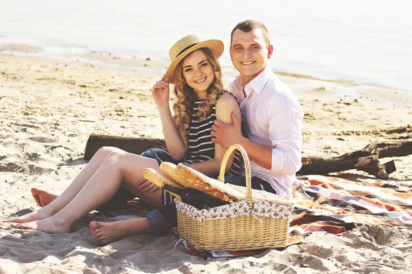 Ona sarılmak seviyorum. Genç yakışıklı adam onun güzel kız arkadaşı sarılma ve Kumsalda piknik yaparken gülümseyen rahat kıyafet içinde yatay çekim.