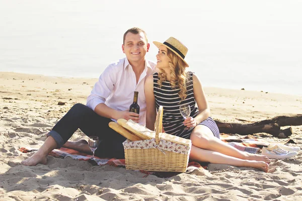 Heureux ensemble. Plan horizontal de belle jeune femme regardant son petit ami qui regarde la caméra tout en pique-niquant ensemble sur la plage . — Photo