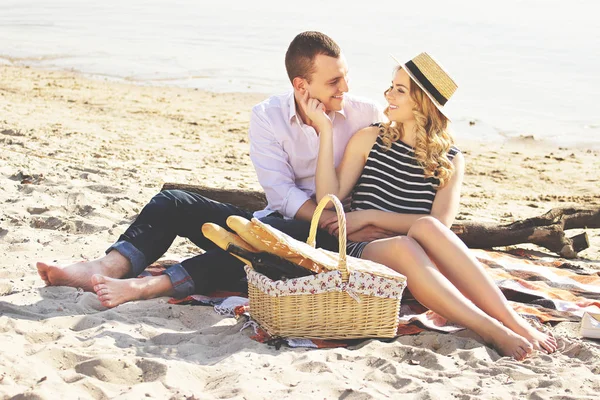 Радий бути разом. Горизонтальний знімок красивої молодої пари, дивлячись один на одного і посміхаючись, маючи пікнік на березі моря . — стокове фото