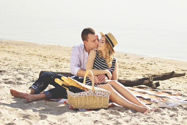 Ти моє щастя. Горизонтальний знімок на людину в повсякденному одязі цілує свою милу дівчину в одязі і посміхається, маючи пікнік на пляжі . — стокове фото