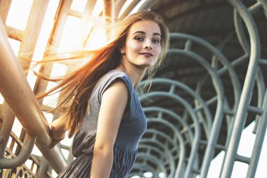 Kentsel moda. Kameraya bakarak ve açık havada şehirde poz süre gülümseyen elbiseli çekici, genç ve şık kadın düşük açılı yan görünüm.