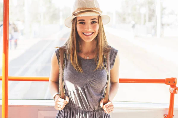 Elle adore voyager. Portrait de belle et jeune femme en robe et chapeau regardant à la caméra et souriant tout en se tenant à l'intérieur du train en mouvement . — Photo