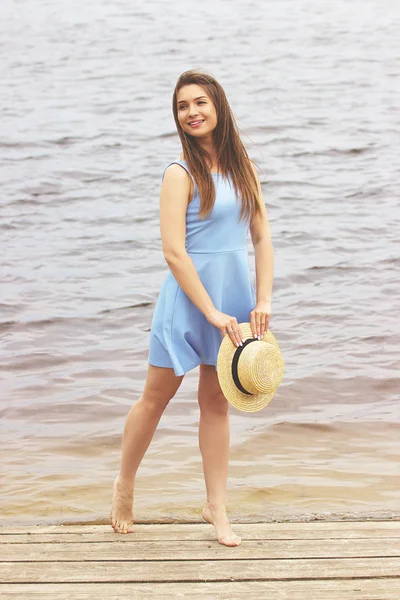 Beauty shines out of her. Full-length shot of cheerful, young and attractive woman in dress looking away and smiling while standing on wooden pier.