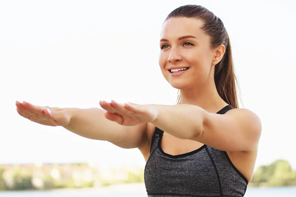 Eine gute Balance. Porträt einer jungen attraktiven Frau in Sportkleidung, die wegschaut und lächelt, während sie am Meer Balanceübungen macht. — Stockfoto