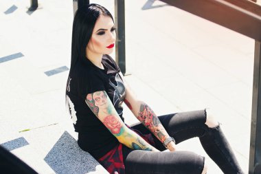 Dövme moda. Kentsel arka planı oturan kırmızı dudaklar ile şık dövmeli hippi kız portresi.