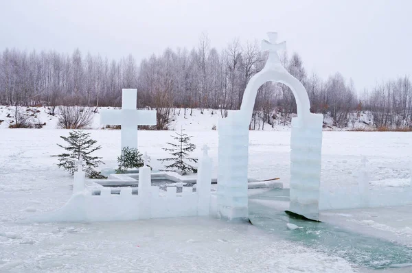 Buz gibi bir günde Epiphany 'deki buz deliğinin yakınındaki bir kış gölünde buza kazınmış haç.