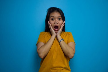 Mavi izole edilmiş geçmişi olan güzel Asyalı kadınların portresi, şok edici bir jest.