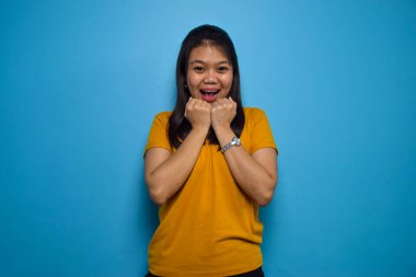Mavi izole edilmiş güzel Asyalı kadınların portresi, mutlu ve heyecanlı bir jest.