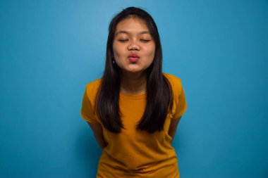 Mavi izole edilmiş geçmişi olan güzel Asyalı kadınların portresi kameraya bakıyor ve öpüşüyorlar.