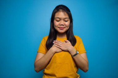 Mavi izole edilmiş geçmişi olan, gülümseyen ve minnettar olan güzel Asyalı kadınların portresi.