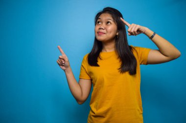 Mavi izole edilmiş arka planı olan güzel Asyalı kadınların portresi sağ tarafı işaret ediyor.