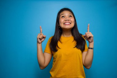 Mavi izole edilmiş arkaplanı olan güzel Asyalı kadınların portresi, fotokopi alanını işaret ediyor.
