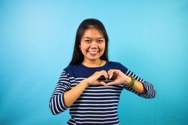 Mavi izole edilmiş geçmişi olan, kalbi iki eliyle şekillendiren güzel Asyalı kadın portresi, aşk jesti.