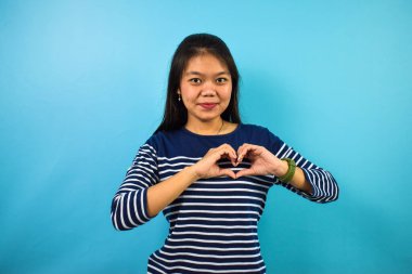 Mavi izole edilmiş geçmişi olan, kalbi iki eliyle şekillendiren güzel Asyalı kadın portresi, aşk jesti.