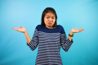 Mavi izole edilmiş, kafası karışık genç Asyalı kadınların portresi.