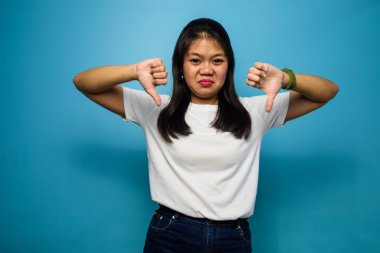 Mavi izole edilmiş arka planı olan beyaz tişört giyen güzel Asyalı kadınların portresi.