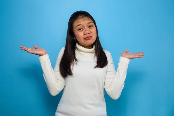 Stock image Portrait of Young beautiful asian women using white T-shirt with blue isolated background, look at the camera and make confused gesture