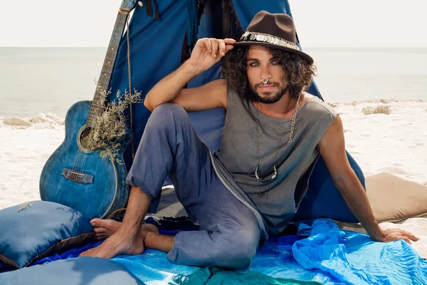 Attractive young gypsy man with guitar sitting on pillows at tep — ストック写真